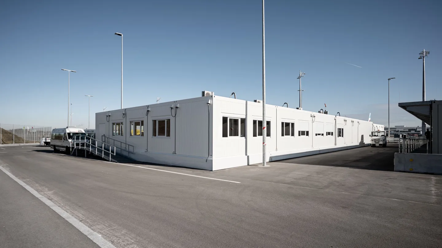 Die 650 m² große Interimskantine am Flughafen München von außen: eine langgestreckte weiße Containeranlage auf dem Vorfeld.