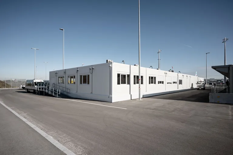 Die 650 m² große Interimskantine am Flughafen München von außen: eine langgestreckte weiße Containeranlage auf dem Vorfeld.