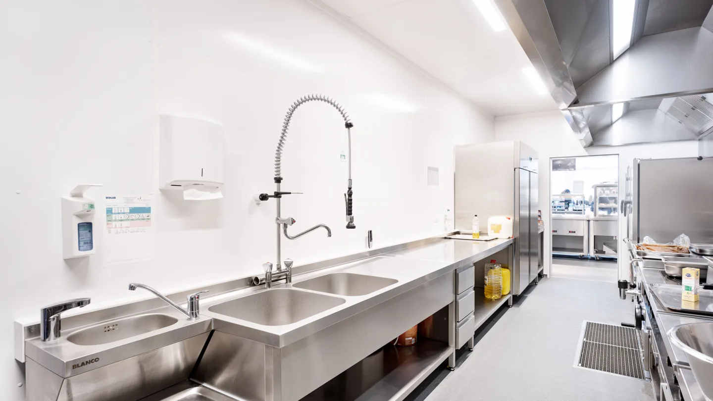 Spülbereich im Küchencontainer: Edelstahlbecken mit Vorspülbrause und durchgehender Arbeitszeile.
