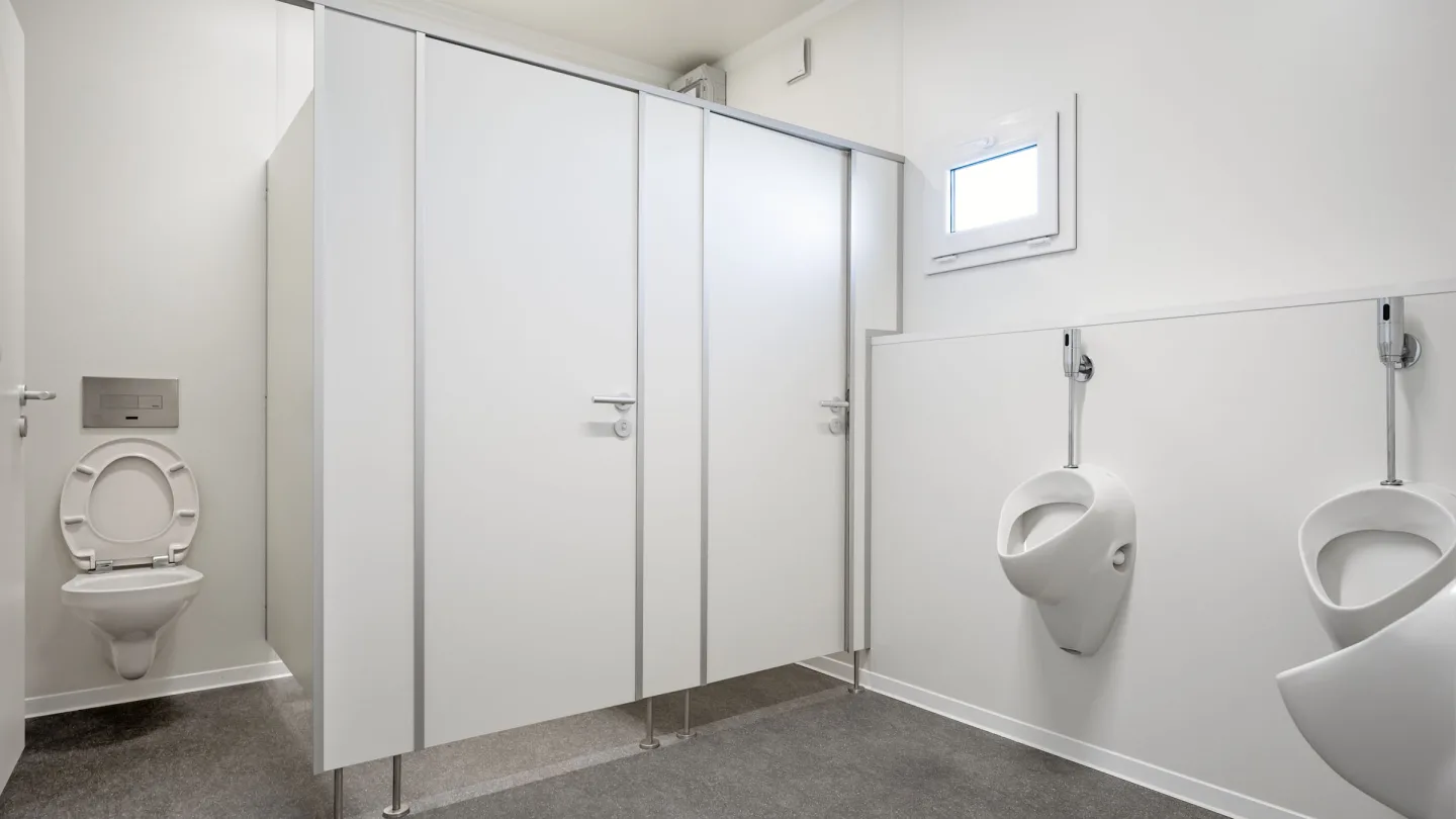Innenansicht eines Sanitärcontainers mit WC-Kabinen und Urinalen.