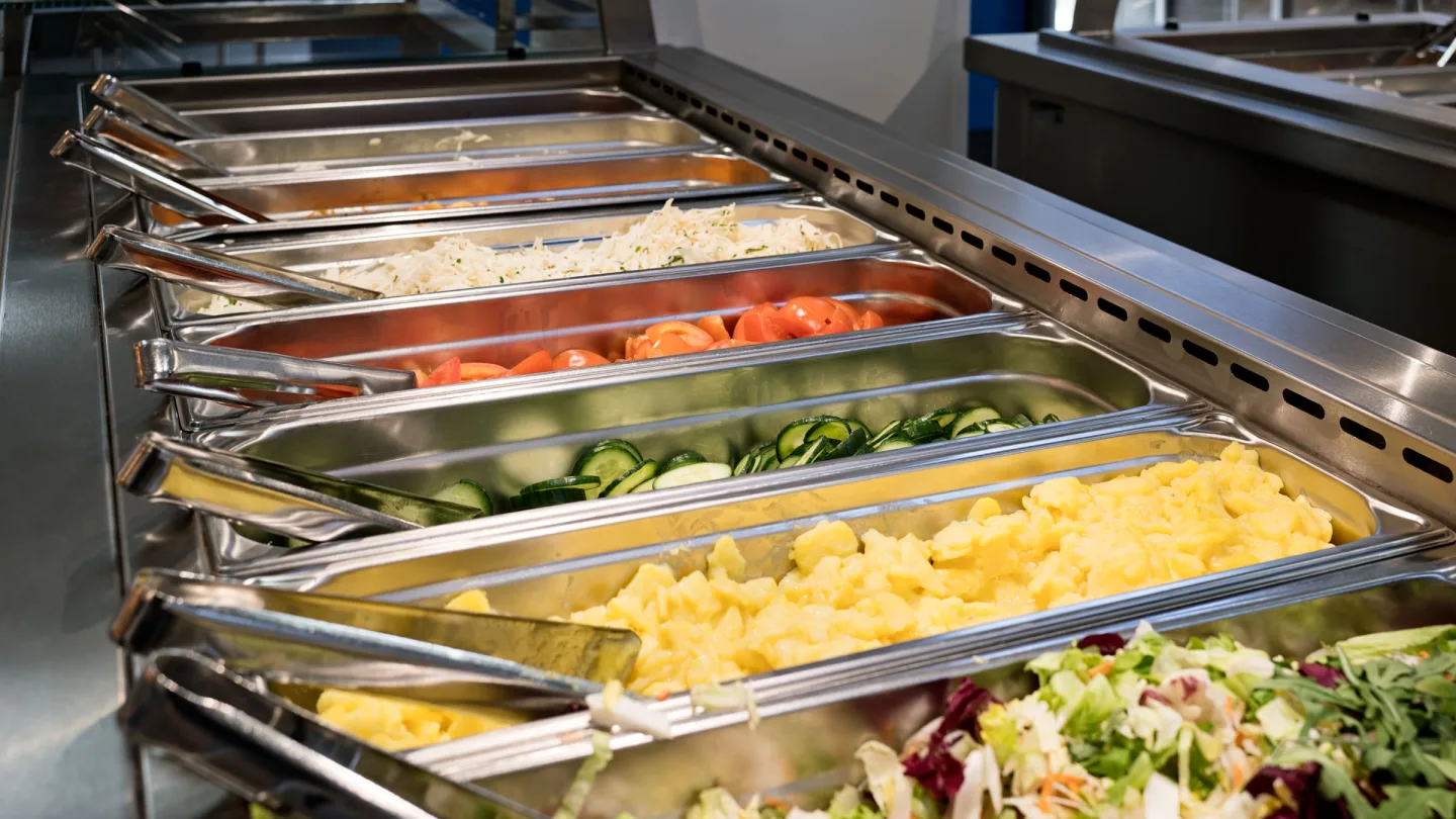 Warmhaltetheke mit Gastronorm-Behältern voller Salate, Gemüse und warmer Speisen.