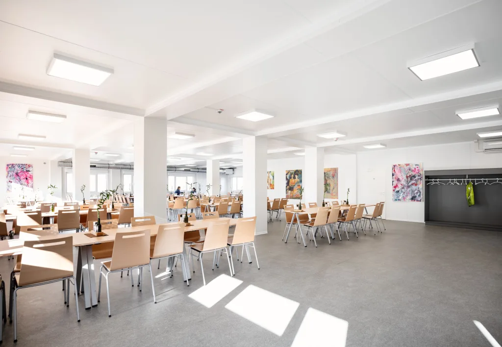 Der Speisesaal aus anderer Blickrichtung: Tageslicht, Wandbilder und Garderobenhaken.