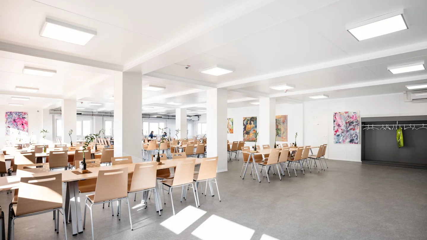 Der Speisesaal aus anderer Blickrichtung: Tageslicht, Wandbilder und Garderobenhaken.